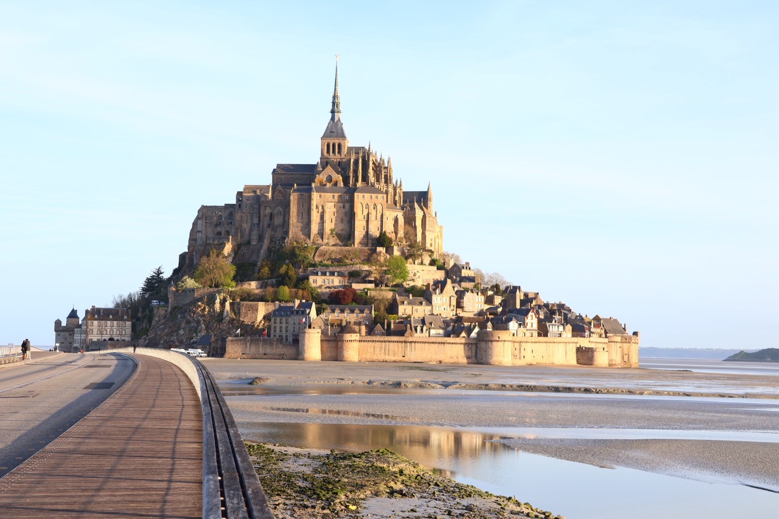 朝日に照らされ引き潮の干潟に立つモンサンミッシェルの全景(本土側の橋から)