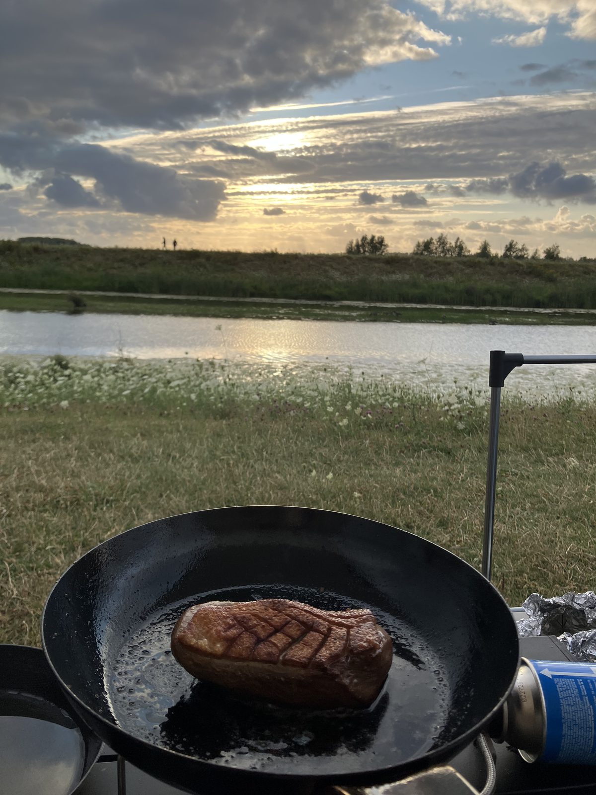 夕暮れのキャンプサイトでフライパンで焼く鴨胸肉