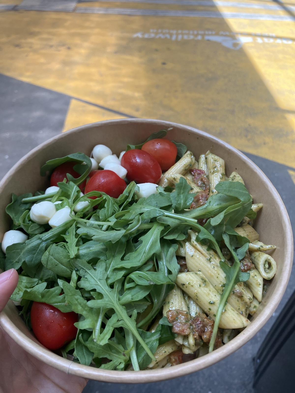手に持ったCoopのパスタサラダ。ルッコラ・モッツァレラ・ドライトマト入り