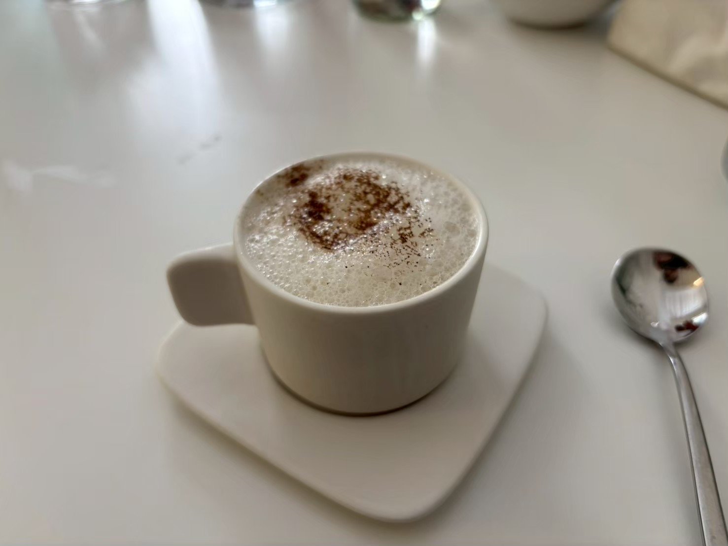 カップに注がれたきのこのスープ。表面が泡立てられ、上に茶色い粉がふられている