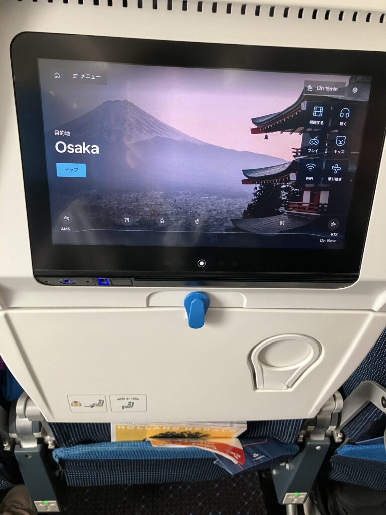 AMS発関空行きのモニター。目的地Osaka、到着まで残り12時間15分の表示