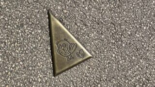 ディジョンの歩道に埋め込まれた「フクロウの小径」のブロンズ三角プレート