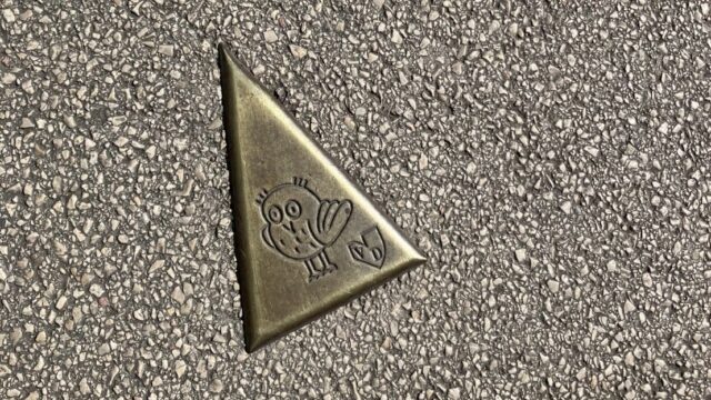 ディジョンの歩道に埋め込まれた「フクロウの小径」のブロンズ三角プレート