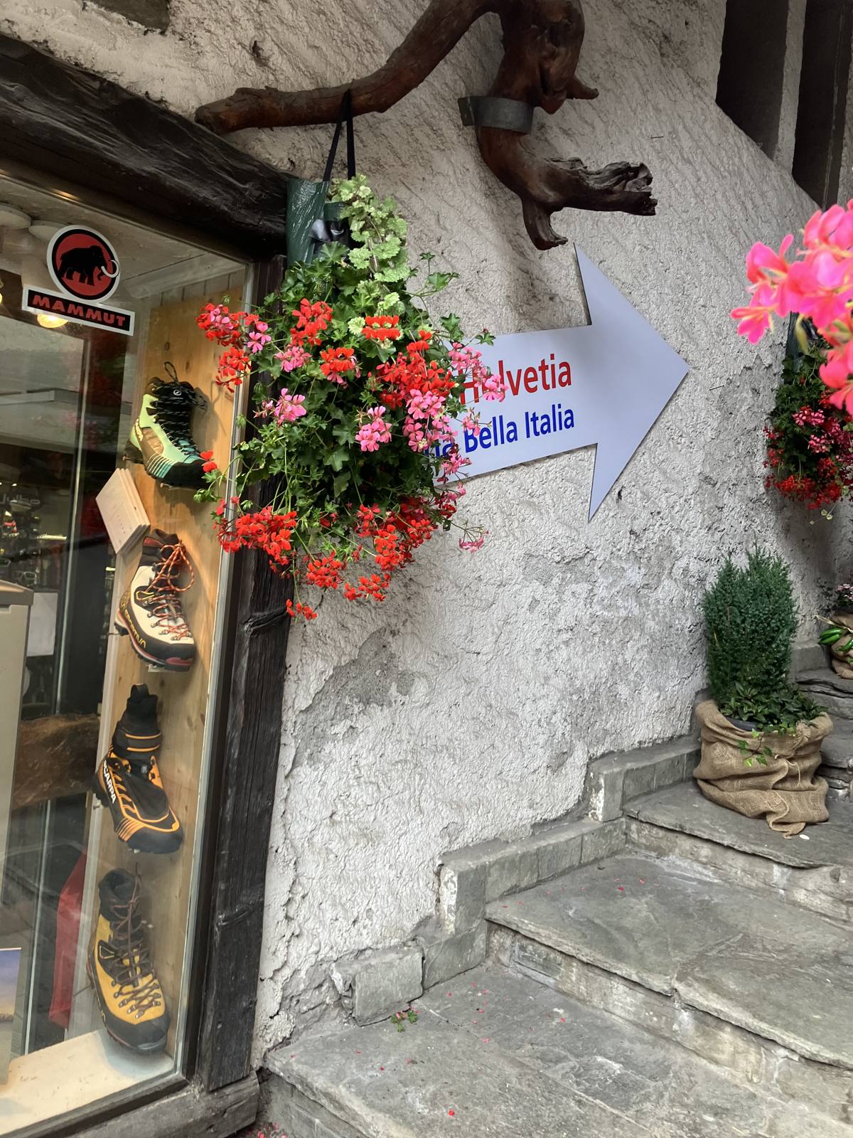 ホテル・ヘルヴェティアの入口を示す案内看板。登山用品店のウィンドウの脇